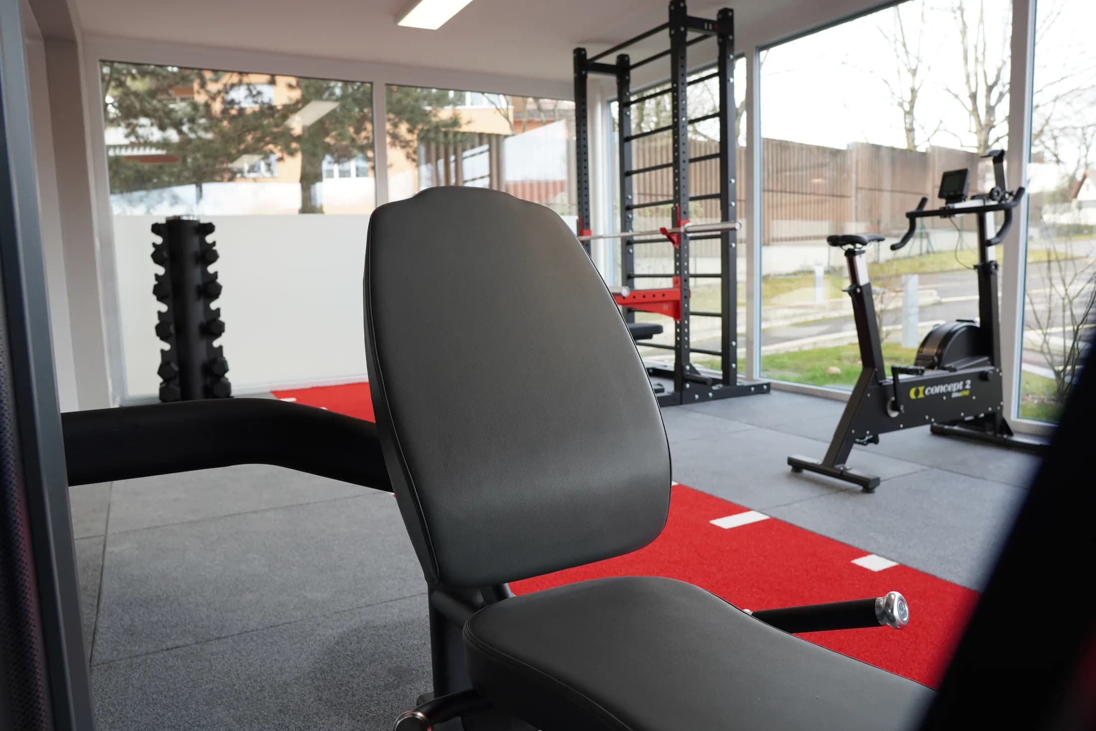 Cage de musculation, banc réglable et vélo du plateau technique, devant les baies vitrées