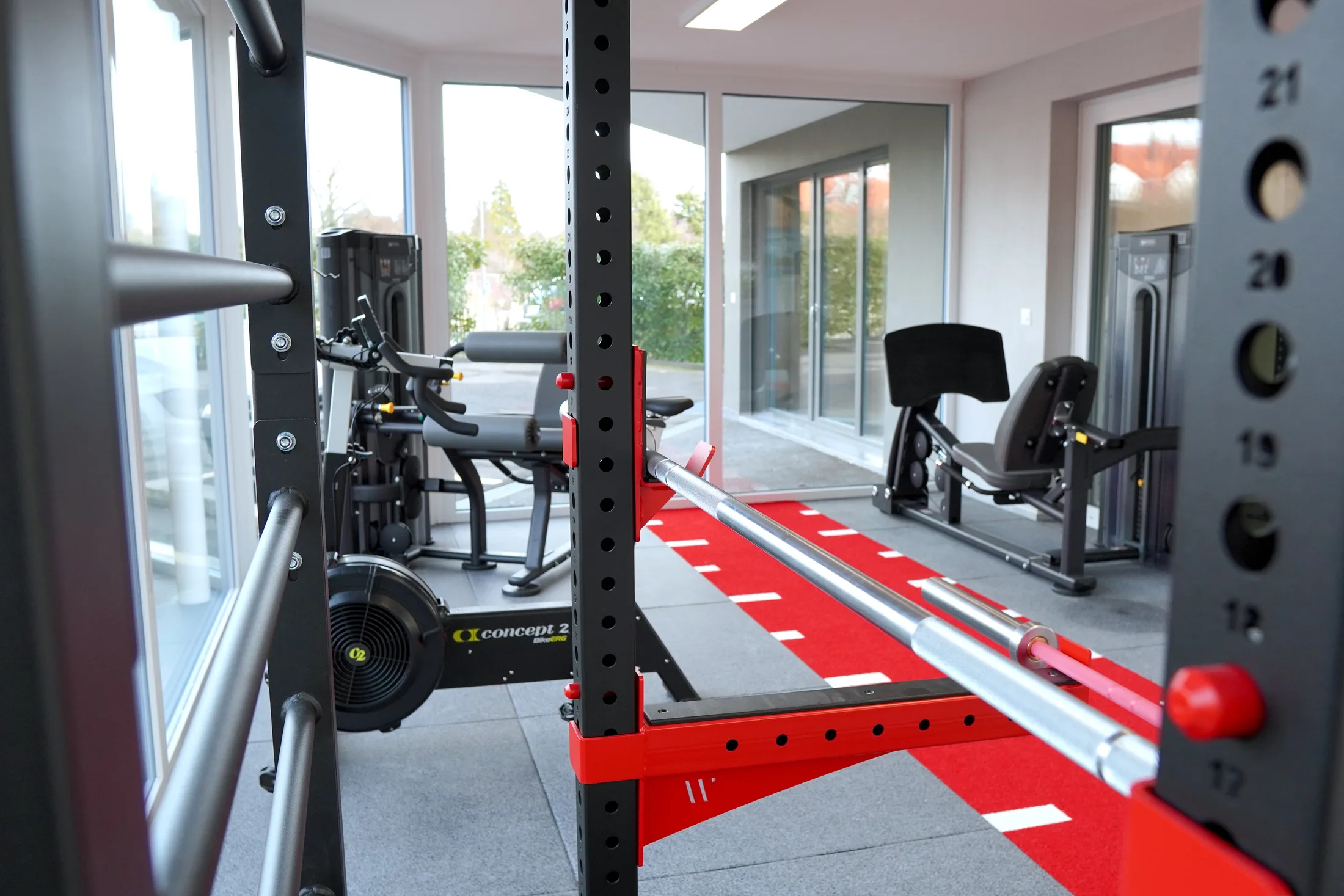 Barre de musculation, rameur et sol rouge du plateau technique de rééducation
